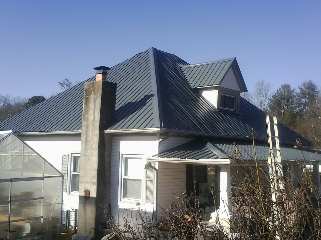 Dark blue standing seam metal roof on a white farmhouse with dormer — Slate & Tile Roof Repair by Roofing Brothers in Carversville