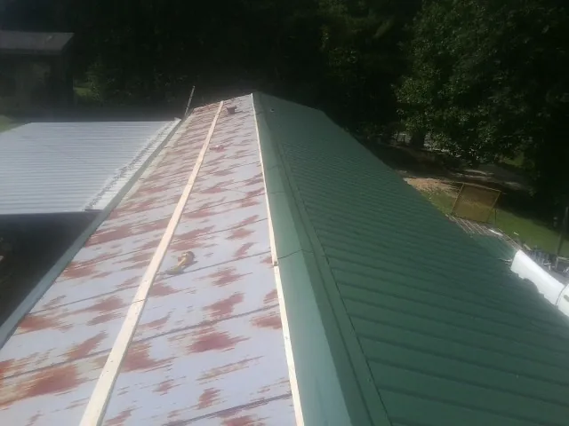 Old rusted panels beside newly installed green metal roofing — Wind Damage Roof Repair by Roofing Brothers in Carversville