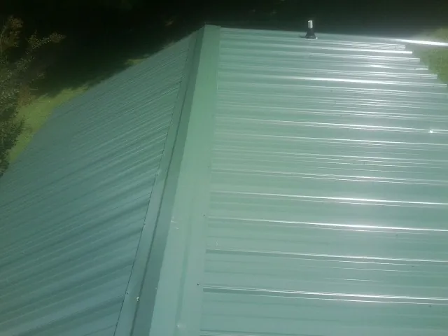 New green metal panels meeting at the ridge of a roof — Flat Roof Repair work by our crew in Carversville