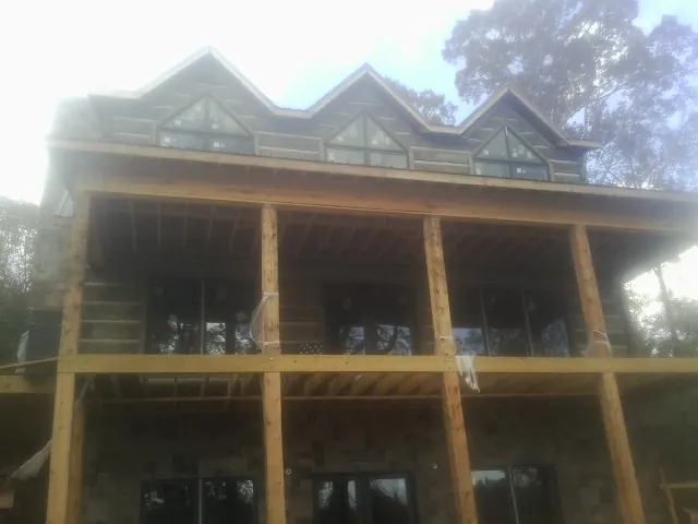 Dormers and porch framing on a large log home under construction — Roof Coating work by our crew in Carversville