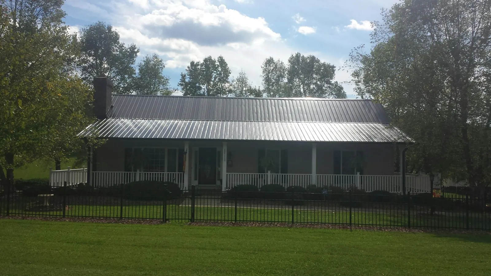 Gray metal roof on a brick ranch with a full width front porch — Gutter Guard Installation work by our crew in Carversville