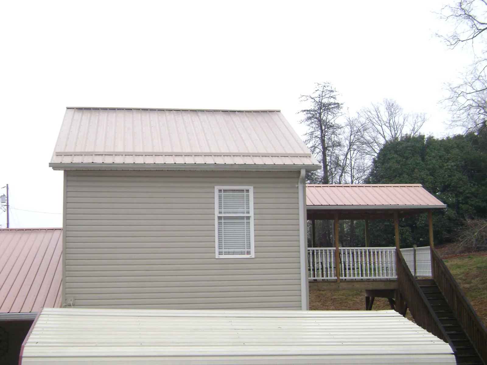 Tan metal roofs on a two story addition and attached porch, from a Roof Replacement job in Carversville