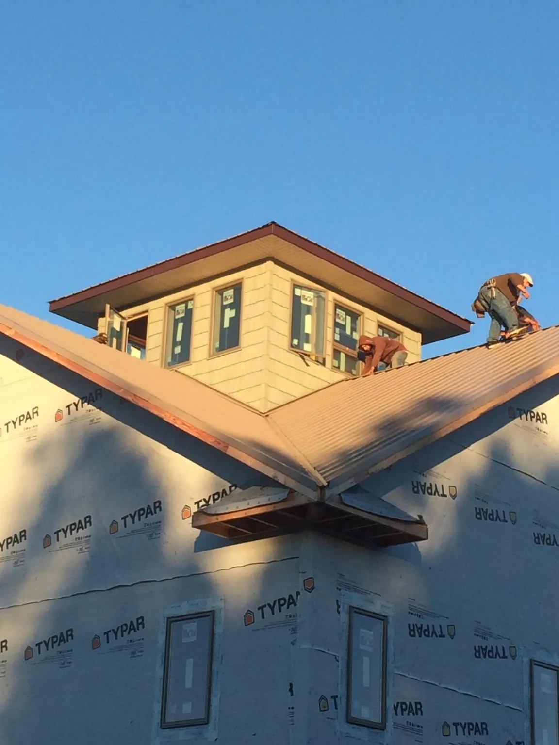 Roofers working around a rooftop cupola on a new metal roof at sunset — Roof Waterproofing in Carversville by Roofing Brothers